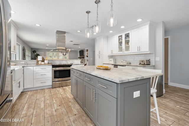 kitchen featuring a kitchen island, white cabinetry, appliances with stainless steel finishes, a kitchen bar, and gray cabinets