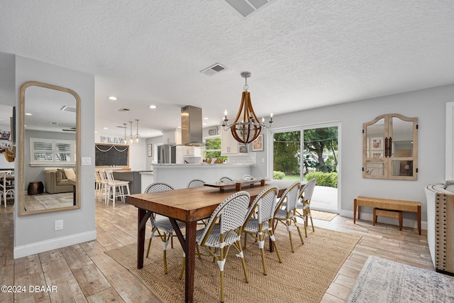 dining room with a textured ceiling, a notable chandelier, and light hardwood / wood-style flooring