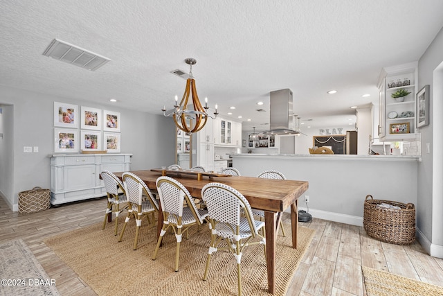 dining room featuring light hardwood / wood-style floors, a chandelier, and a textured ceiling