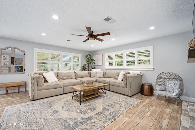 living room with a textured ceiling, light wood-type flooring, plenty of natural light, and ceiling fan