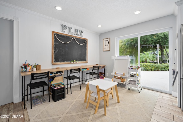 dining area with a textured ceiling, light wood-type flooring, and crown molding