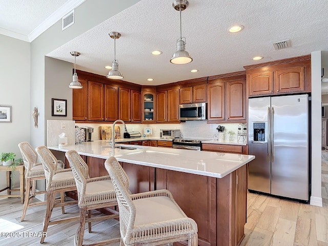 kitchen featuring a breakfast bar, a peninsula, a sink, stainless steel appliances, and glass insert cabinets