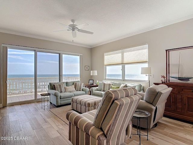 living room featuring light wood-style flooring, a textured ceiling, ceiling fan, and ornamental molding