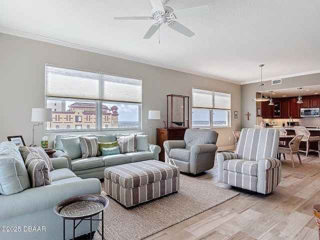 living room with light wood-style floors, ceiling fan, crown molding, and a textured ceiling