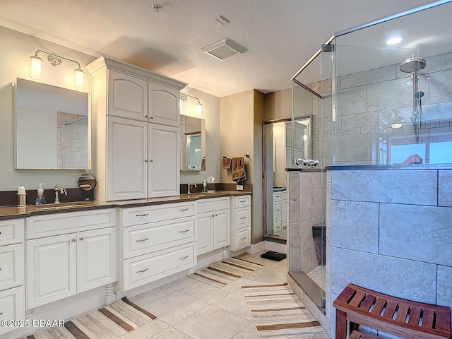 bathroom featuring a sink, double vanity, a textured ceiling, and tiled shower