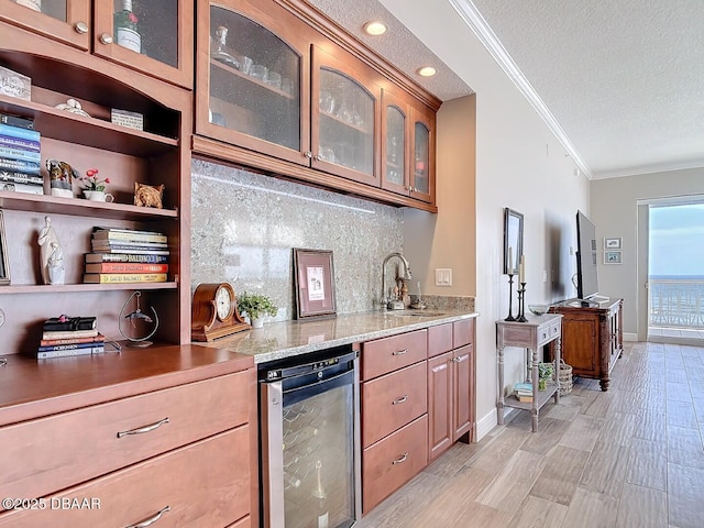 kitchen featuring beverage cooler, open shelves, a sink, a textured ceiling, and crown molding