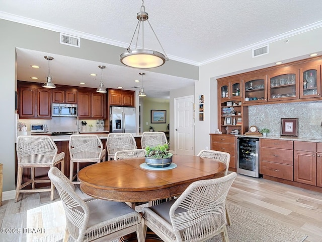 dining area with visible vents, a textured ceiling, beverage cooler, and crown molding