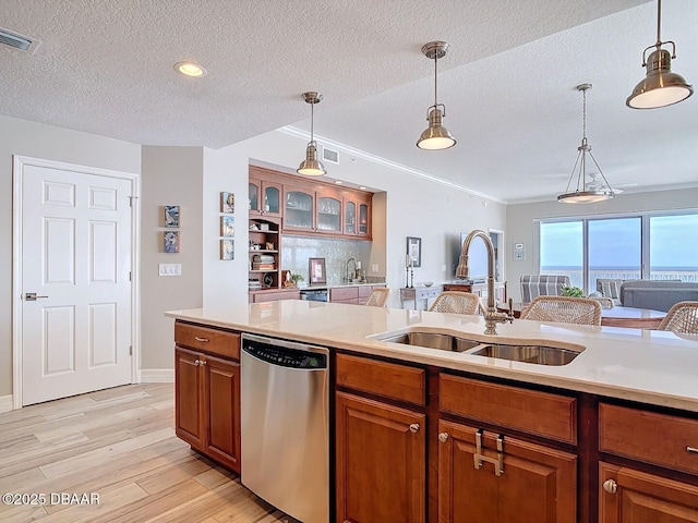 kitchen with visible vents, dishwasher, light countertops, brown cabinets, and a sink