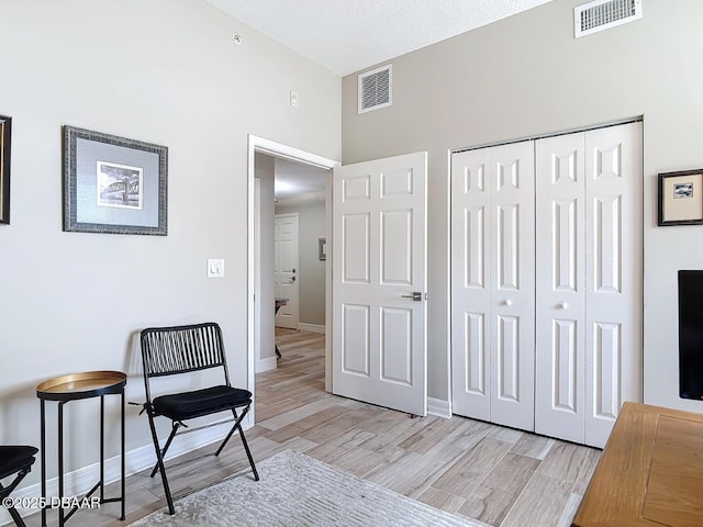 living area featuring visible vents, baseboards, and light wood finished floors