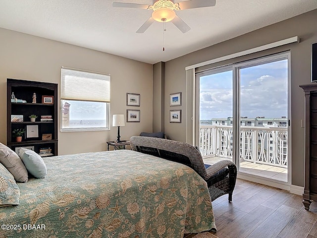 bedroom with a ceiling fan, access to outside, multiple windows, and wood finished floors