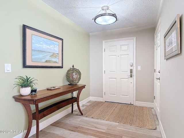 entrance foyer featuring baseboards, light wood-type flooring, and a textured ceiling