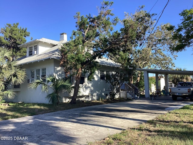 268 Hartford Ave, Daytona Beach, FL 32118 - view of side of property with concrete driveway, stucco siding, an attached carport, and a chimney