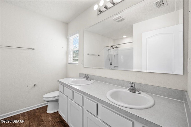 bathroom featuring hardwood / wood-style flooring, vanity, a textured ceiling, a shower, and toilet