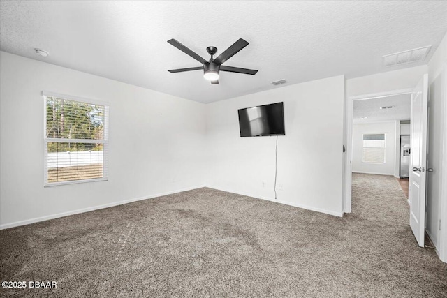 carpeted spare room with ceiling fan, a textured ceiling, and a wealth of natural light