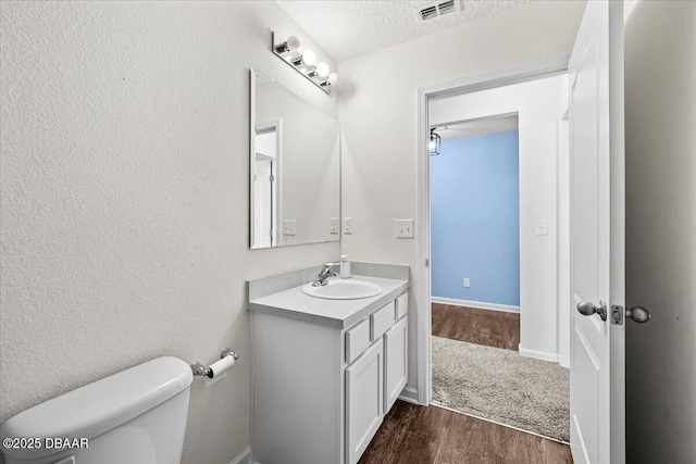 bathroom with vanity, hardwood / wood-style floors, toilet, and a textured ceiling