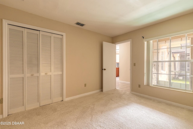 unfurnished bedroom featuring light carpet, multiple windows, and a closet