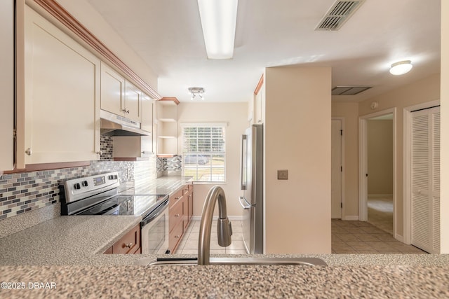 kitchen with light stone countertops, appliances with stainless steel finishes, tasteful backsplash, sink, and light tile patterned flooring