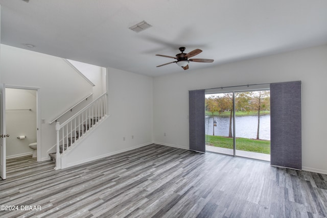 unfurnished living room with a water view, ceiling fan, and light hardwood / wood-style flooring