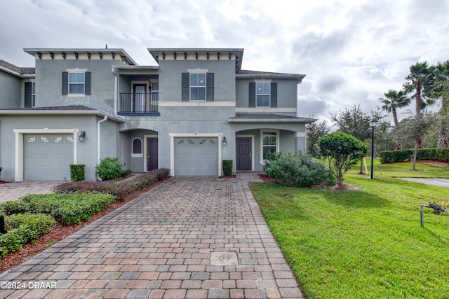 view of front of home featuring a balcony, a garage, and a front yard