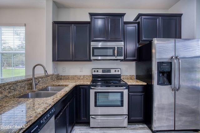 kitchen featuring light stone counters, sink, light hardwood / wood-style flooring, and appliances with stainless steel finishes