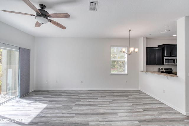 interior space featuring ceiling fan with notable chandelier, light hardwood / wood-style floors, and a healthy amount of sunlight