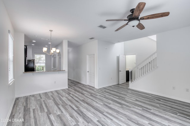 unfurnished living room featuring light wood-type flooring, sink, and ceiling fan with notable chandelier