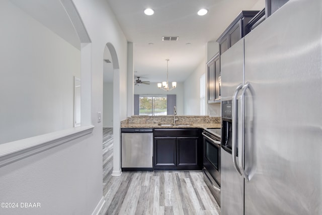 kitchen with light hardwood / wood-style flooring, sink, light stone countertops, pendant lighting, and appliances with stainless steel finishes