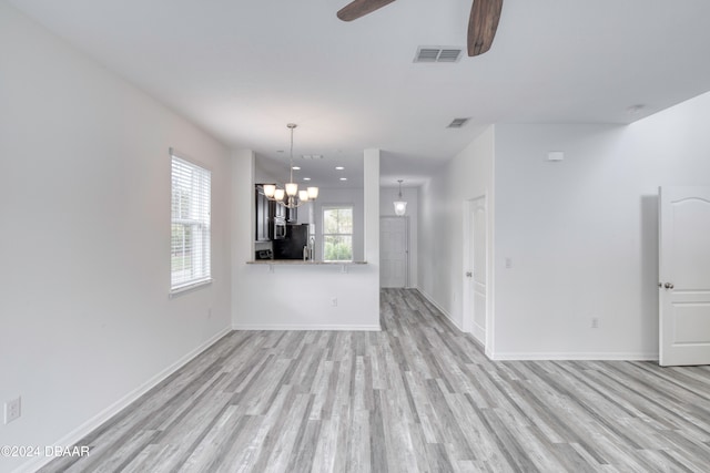 unfurnished living room featuring light wood-type flooring and ceiling fan with notable chandelier