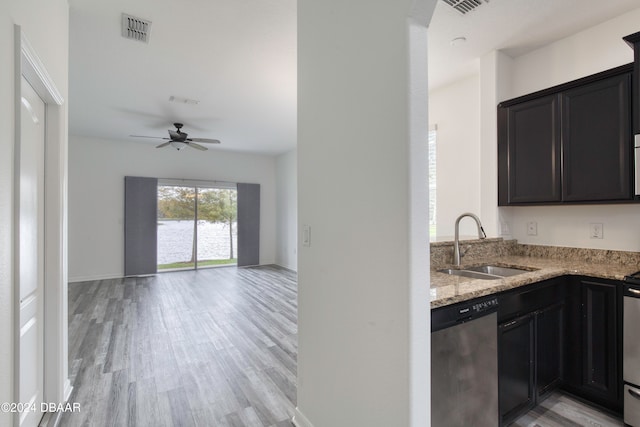 kitchen with stainless steel appliances, light stone counters, sink, ceiling fan, and light hardwood / wood-style flooring