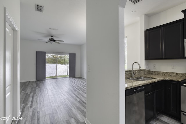 123 Langston Dr, Daytona Beach, FL 32124 - kitchen with stainless steel dishwasher, a sink, light stone counters, light wood finished floors, and dark cabinets