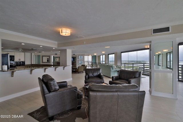 interior space featuring baseboards, visible vents, ornamental molding, and a raised ceiling