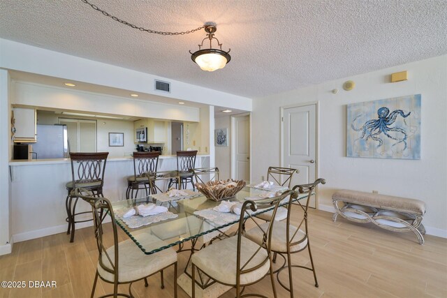 3855 S Atlantic Ave S Unit 1405, Daytona Beach, FL 32118 - dining room featuring light wood-style floors, baseboards, a textured ceiling, and visible vents