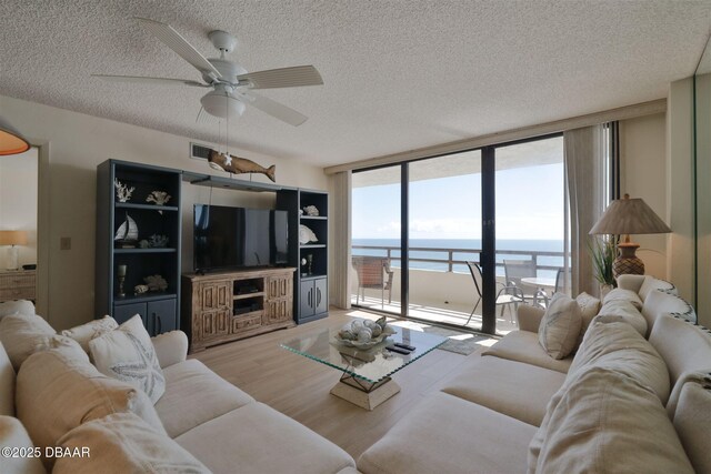 3855 S Atlantic Ave S Unit 1405, Daytona Beach, FL 32118 - living room featuring ceiling fan, a wall of windows, light wood-style floors, a textured ceiling, and visible vents