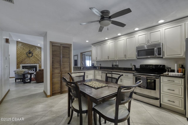 29 Concord Dr, Ormond Beach, FL 32176 - kitchen with stainless steel appliances, dark countertops, recessed lighting, a fireplace, and light tile patterned floors