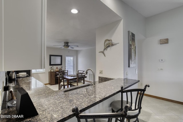 29 Concord Dr, Ormond Beach, FL 32176 - kitchen with a ceiling fan, a peninsula, a kitchen bar, and dark stone countertops