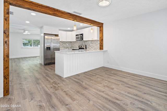 kitchen with white cabinets, light wood-type flooring, stainless steel appliances, and beamed ceiling