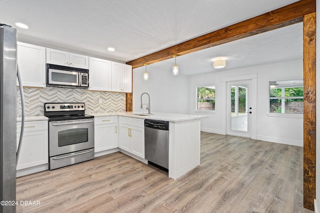 kitchen featuring stainless steel appliances, kitchen peninsula, white cabinetry, light hardwood / wood-style flooring, and decorative light fixtures