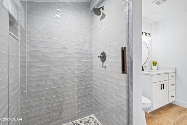 bathroom featuring hardwood / wood-style floors, a shower with shower door, vanity, and toilet