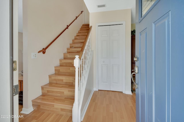 foyer featuring light wood-type flooring, visible vents, stairway, and baseboards