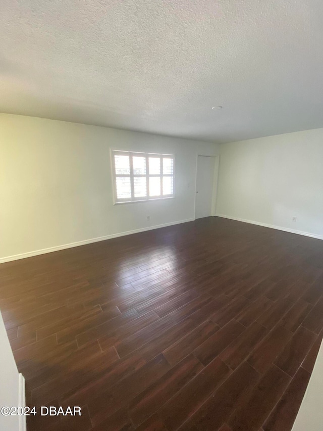 empty room featuring dark wood-type flooring and a textured ceiling