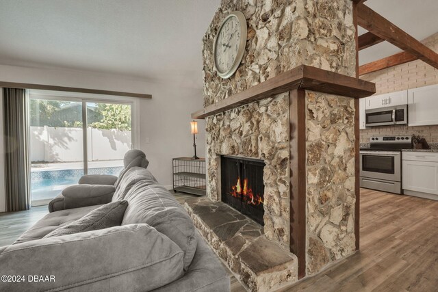 living room with a fireplace, wood-type flooring, and beamed ceiling