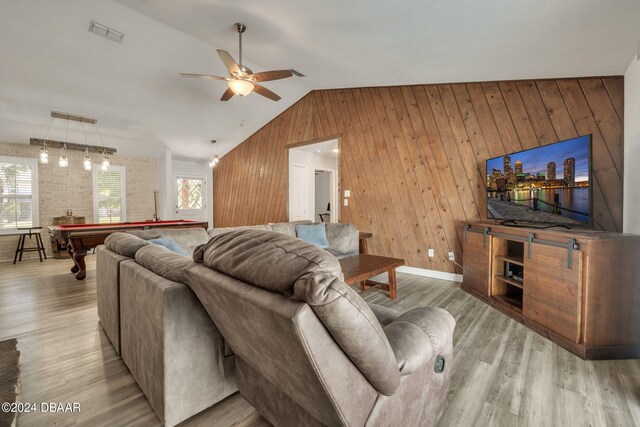 living room featuring wood walls, vaulted ceiling, light hardwood / wood-style floors, pool table, and ceiling fan