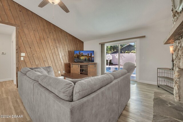 living room with high vaulted ceiling, light hardwood / wood-style flooring, wooden walls, and ceiling fan