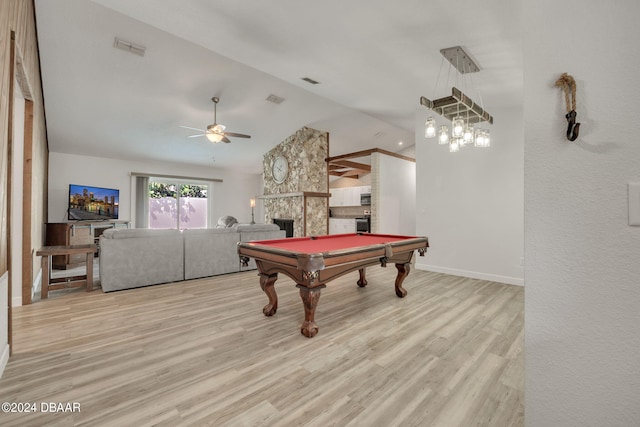 playroom featuring a stone fireplace, pool table, lofted ceiling, ceiling fan, and light hardwood / wood-style flooring