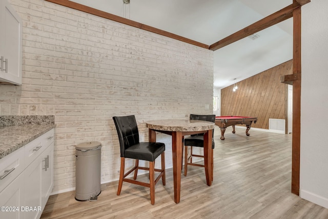 dining area featuring pool table, wooden walls, lofted ceiling with beams, light hardwood / wood-style flooring, and brick wall