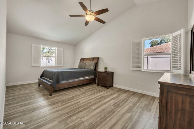 bedroom featuring ceiling fan, multiple windows, light hardwood / wood-style flooring, and high vaulted ceiling