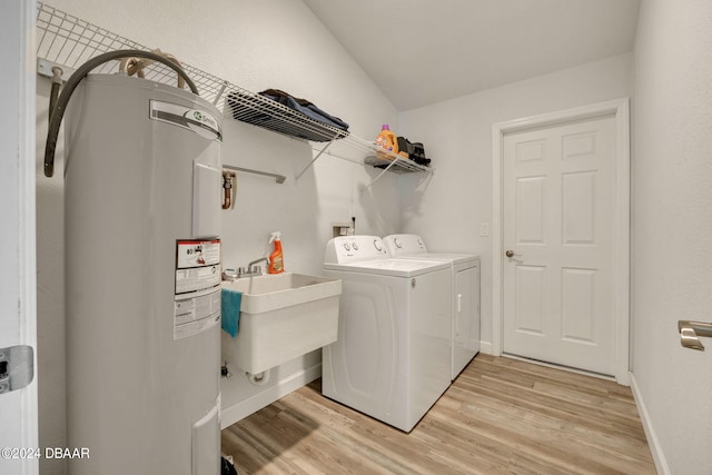 laundry area featuring water heater, sink, independent washer and dryer, and light hardwood / wood-style flooring