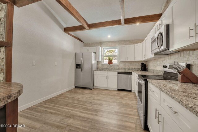 kitchen with stainless steel appliances, light stone counters, tasteful backsplash, white cabinetry, and light hardwood / wood-style flooring