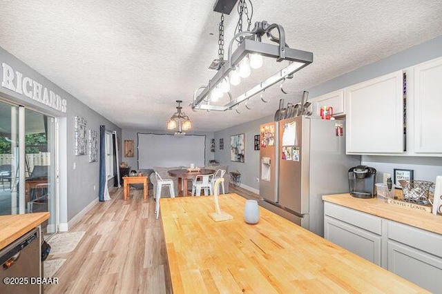 dining room featuring light wood-type flooring and a textured ceiling