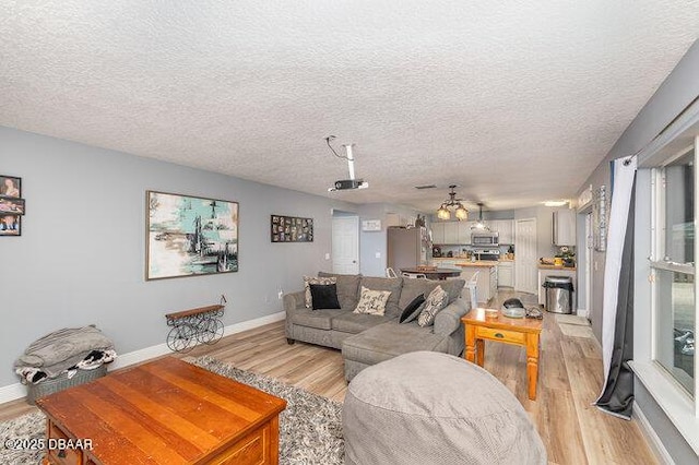 living room with a textured ceiling, light wood-type flooring, and ceiling fan